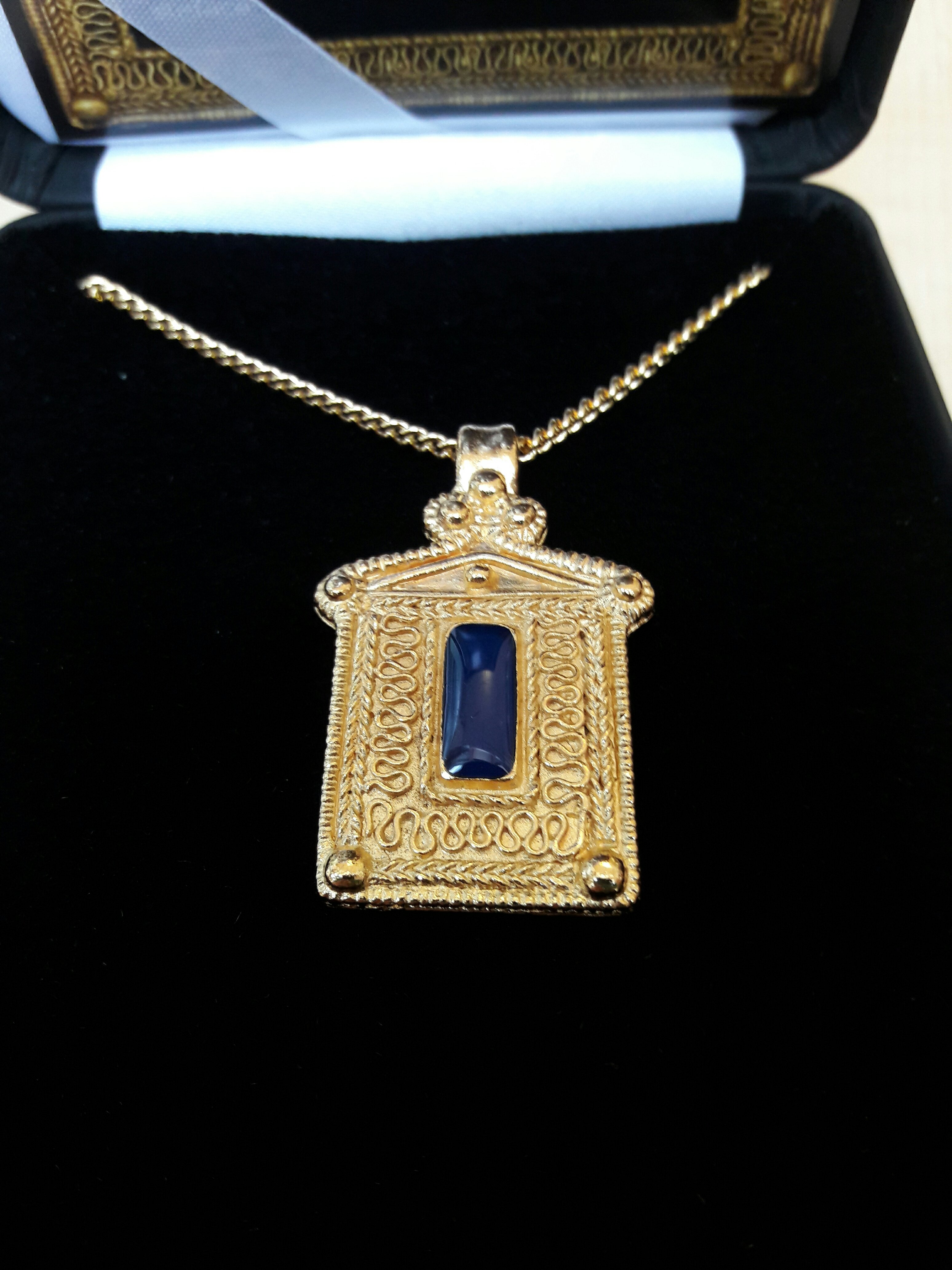 Photo of a reproduction Roman pendant, gold with a dark blue stone in the middle