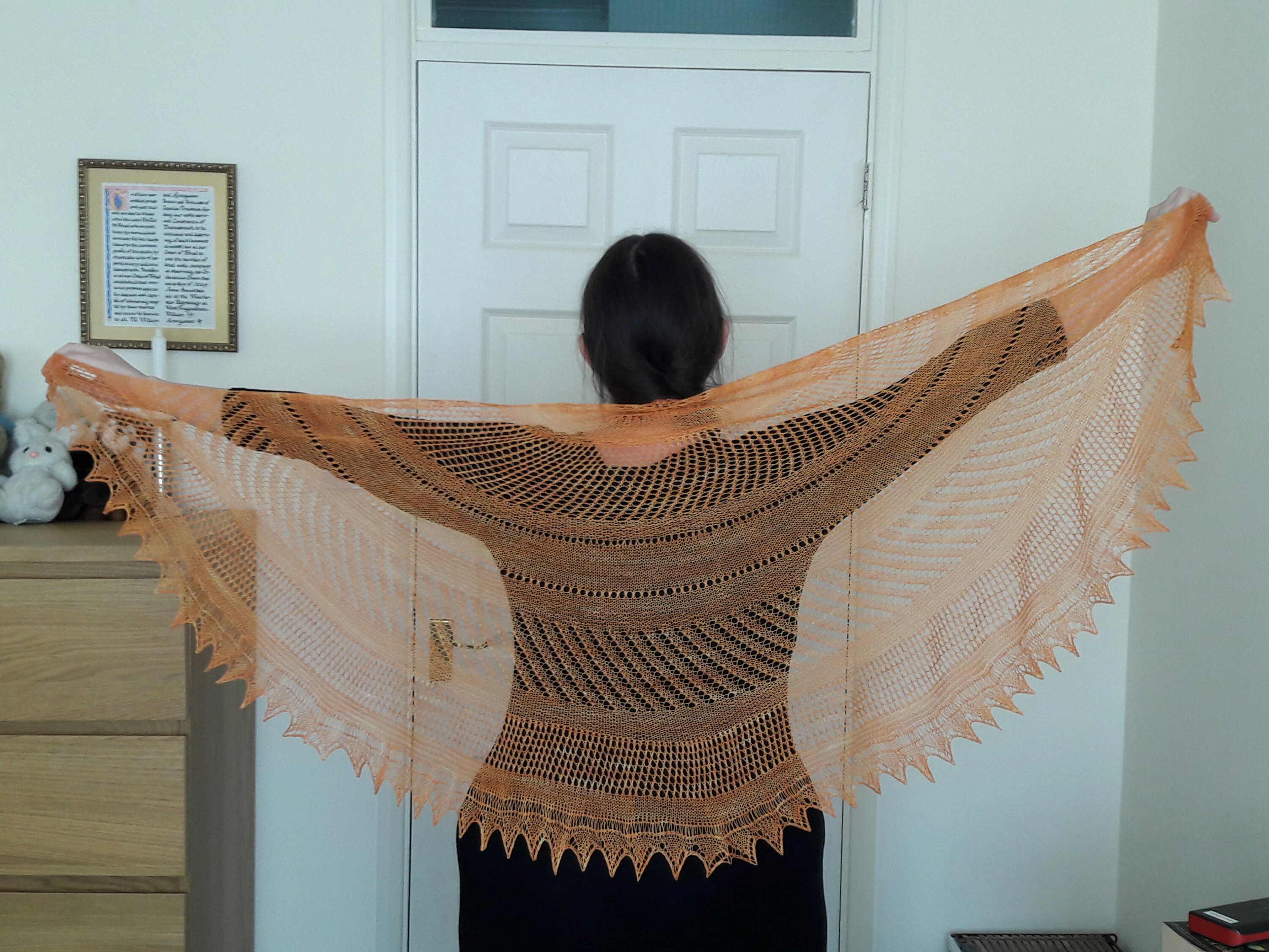 photo of completed shawl being held up by outstretched arms